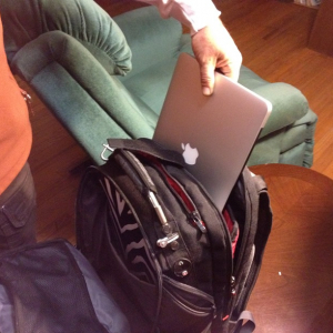 Mans hand pulls Apple computer out of backpack